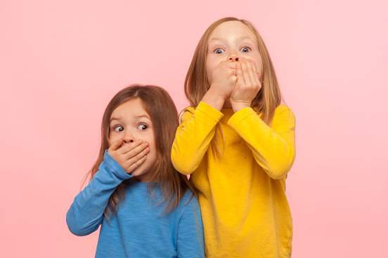 two girls covering their mouths